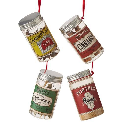 Four spice container ornaments are hanging by their red ribbon string on a white background. Sander's Finest Cloves has a yellow printed label. Franklin and Co Cinnamon have a red printed label. Amelia's Peppermint has a green printed label, and Porter's Nutmeg has a red printed label. 